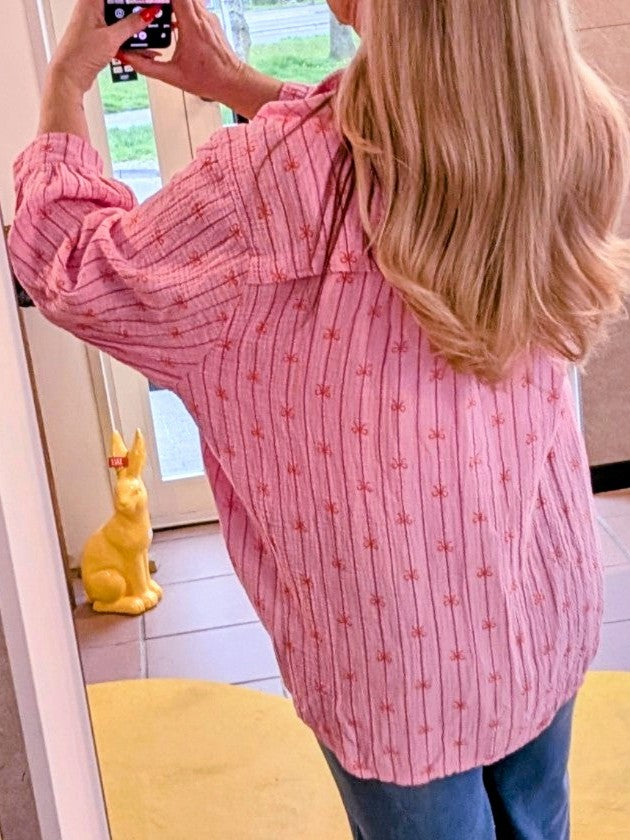 Entdecken Sie unsere wunderschöne Bluse aus Mousselin in einem zarten Rosa Pink und einem ansprechenden Schleifenmuster in Orange. Perfekt für Frühling und Sommer!