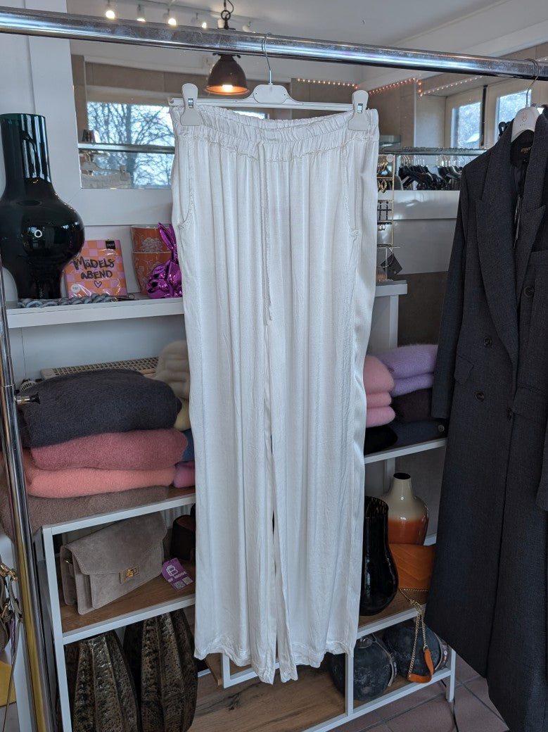Die elegante Hose in Créme aus Satin-Viskose besticht durch ihren edlen Glanz und das weiche fließende Material. Verbinde mühelos Komfort und Eleganz!