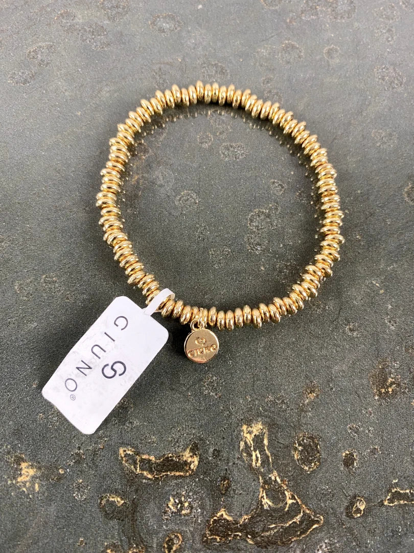 Elastische Armband aus aneinandergereihten goldenen verschiebbaren Metallscheiben mit dekorativer Quaste - perfekt für jeden Anlass, ein echter Hingucker!