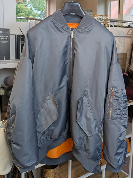 Die oversized Bomberjacke aus hochwertigem Nylon verbindet urbanen Stil mit angenehmem Tragekomfort - mega stylisch in seidigem Blau Grau mit lebendigem Orange!