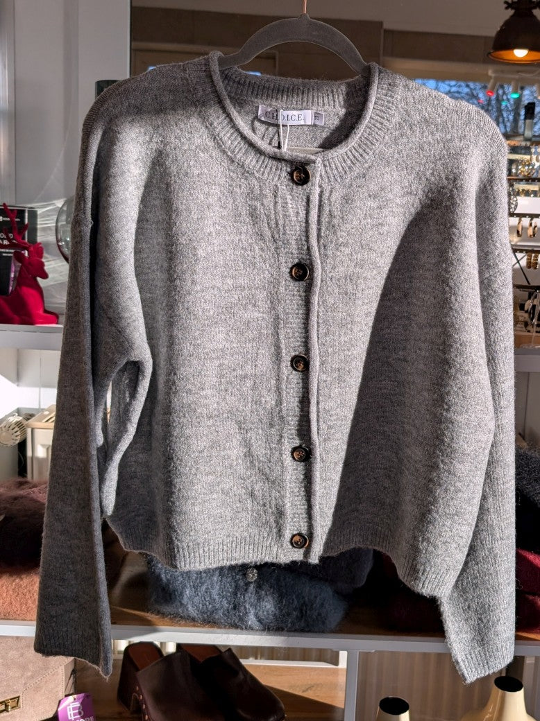 Die gemütliche Strickjacke aus einer hochwertigen Viskose Mischung in elegantem Hellgrau mit braunen Knöpfen verbindet stilvolles Design und Tragekomfort!