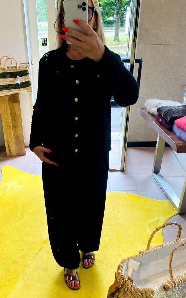 Die schwarze Cardigan-Strickjacke im Chanel-Stil mit ihren markanten Quadrate und edlen Goldknöpfen vereint zeitlose Eleganz mit modernem Komfort!