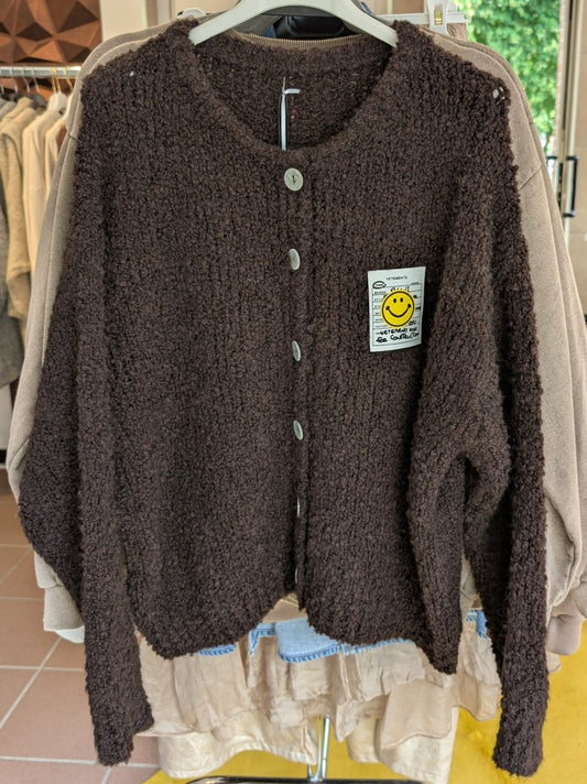 Dies Cardigan-Strickjacke in warmem Coffee Braun bringt mit ihrem gelben Smiley-Aufnäher gute Laune in jeden Look - ein vielseitiges Must-Have!