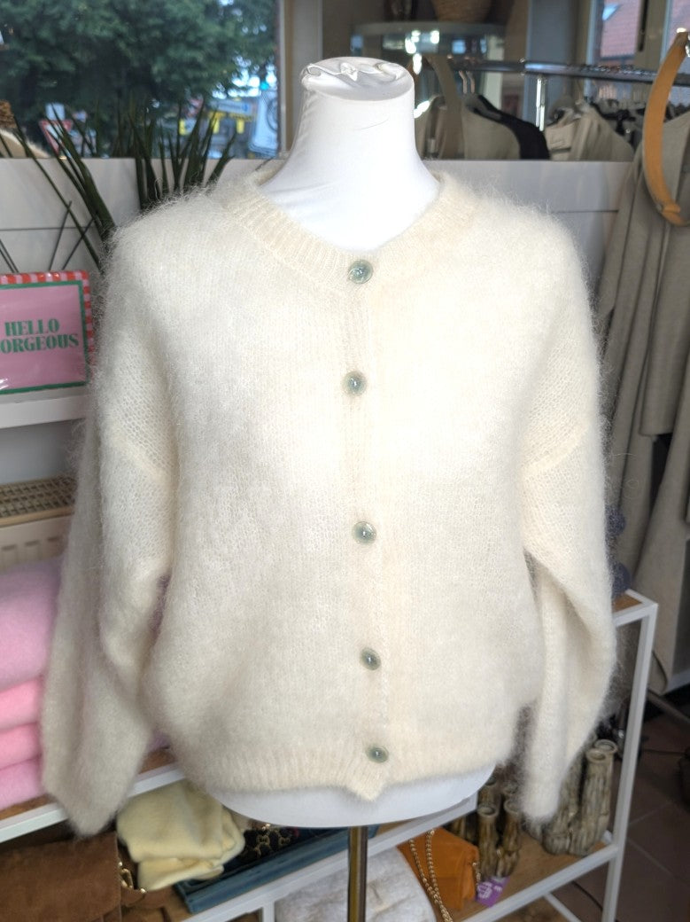 Fühle dich behaglich und stilvoll mit unserer Cardigan Strickjacke aus 80% Soft Kid Mohair Créme Weiß mit hellen Perlmuttknöpfen. Perfekt für alle Gelegenheiten
