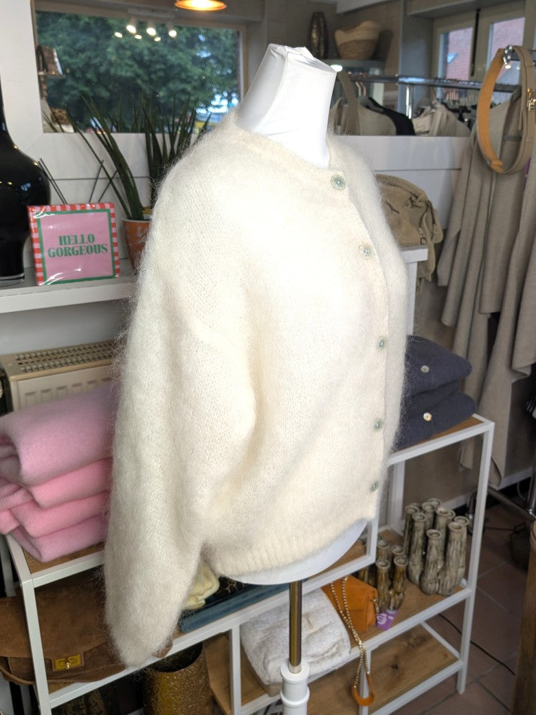 Fühle dich behaglich und stilvoll mit unserer Cardigan Strickjacke aus 80% Soft Kid Mohair Créme Weiß mit hellen Perlmuttknöpfen. Perfekt für alle Gelegenheiten