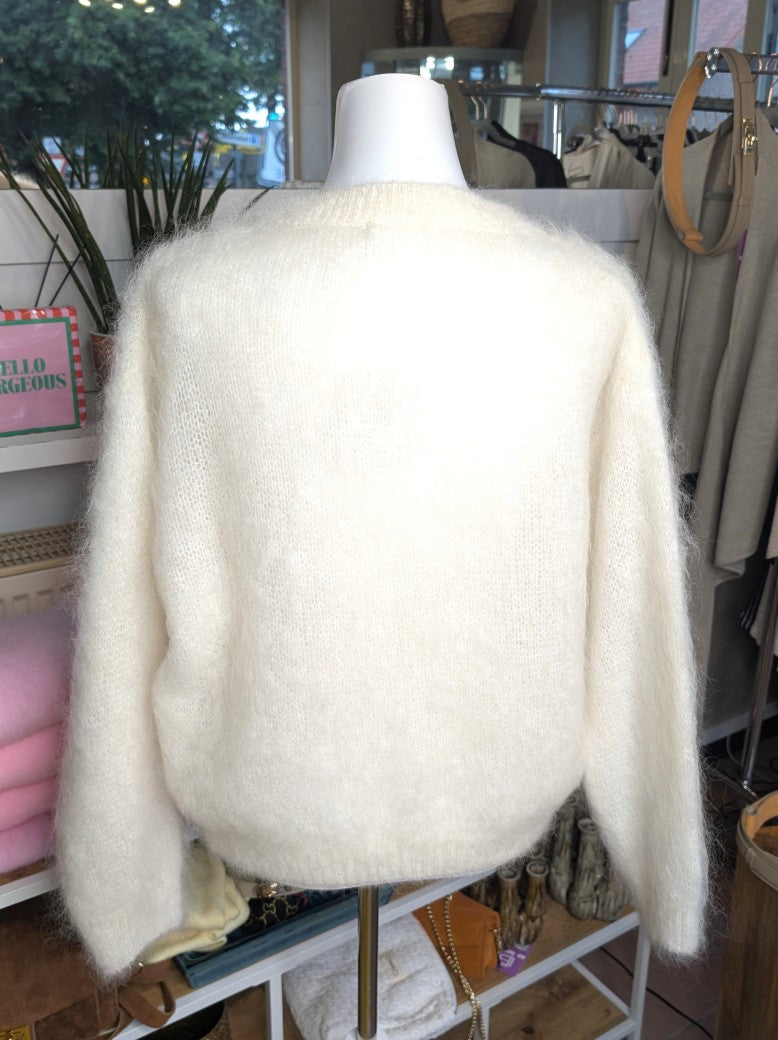 Fühle dich behaglich und stilvoll mit unserer Cardigan Strickjacke aus 80% Soft Kid Mohair Créme Weiß mit hellen Perlmuttknöpfen. Perfekt für alle Gelegenheiten