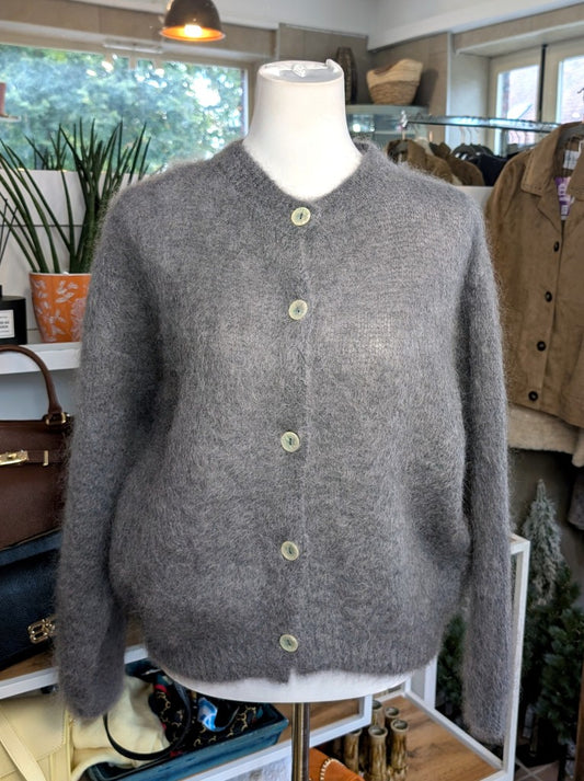 Fühle dich behaglich und stilvoll mit unserer Cardigan Strickjacke aus 80% Soft Kid Mohair Grau mit hellen Perlmuttknöpfen. Perfekt für alle Gelegenheiten
