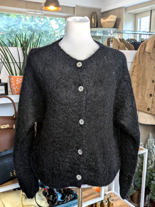 Fühle dich behaglich und stilvoll mit unserer Cardigan Strickjacke aus 80% Soft Kid Mohair Schwarz mit hellen Perlmuttknöpfen. Perfekt für alle Gelegenheiten