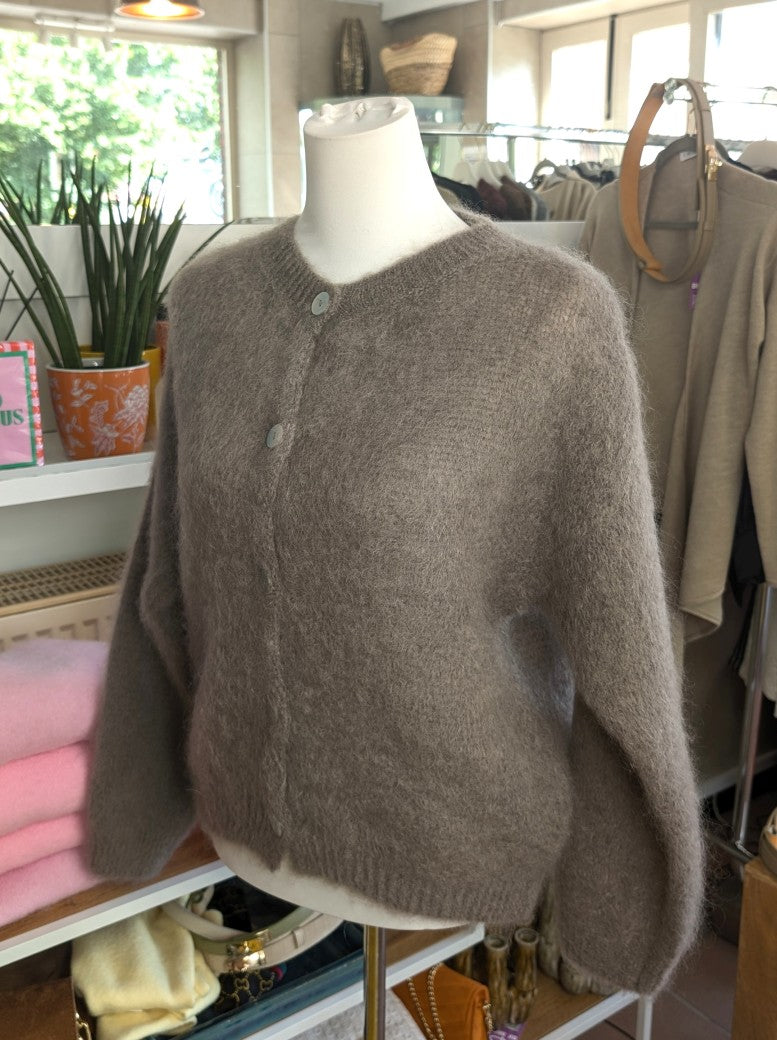 Fühle dich behaglich und stilvoll mit unserer Cardigan Strickjacke aus 80% Soft Kid Mohair Taupe mit hellen Perlmuttknöpfen. Perfekt für alle Gelegenheiten