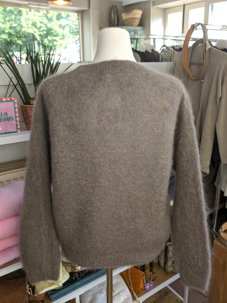 Fühle dich behaglich und stilvoll mit unserer Cardigan Strickjacke aus 80% Soft Kid Mohair Taupe mit hellen Perlmuttknöpfen. Perfekt für alle Gelegenheiten