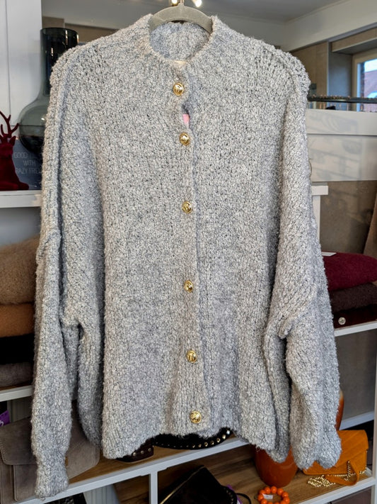 Der elegante Cardigan besticht durch hochwertige Bouclé-Struktur in zartem Hellgrau mit glänzenden Goldknöpfen – zeitloser Klassiker für jeden Kleiderschrank!