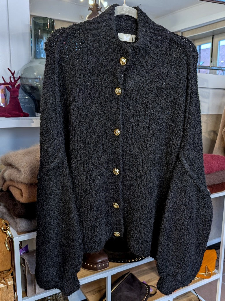 Der elegante Cardigan besticht durch hochwertige Bouclé-Struktur in elegantem Schwarz mit glänzenden Goldknöpfen – zeitloser Klassiker für jeden Kleiderschrank!