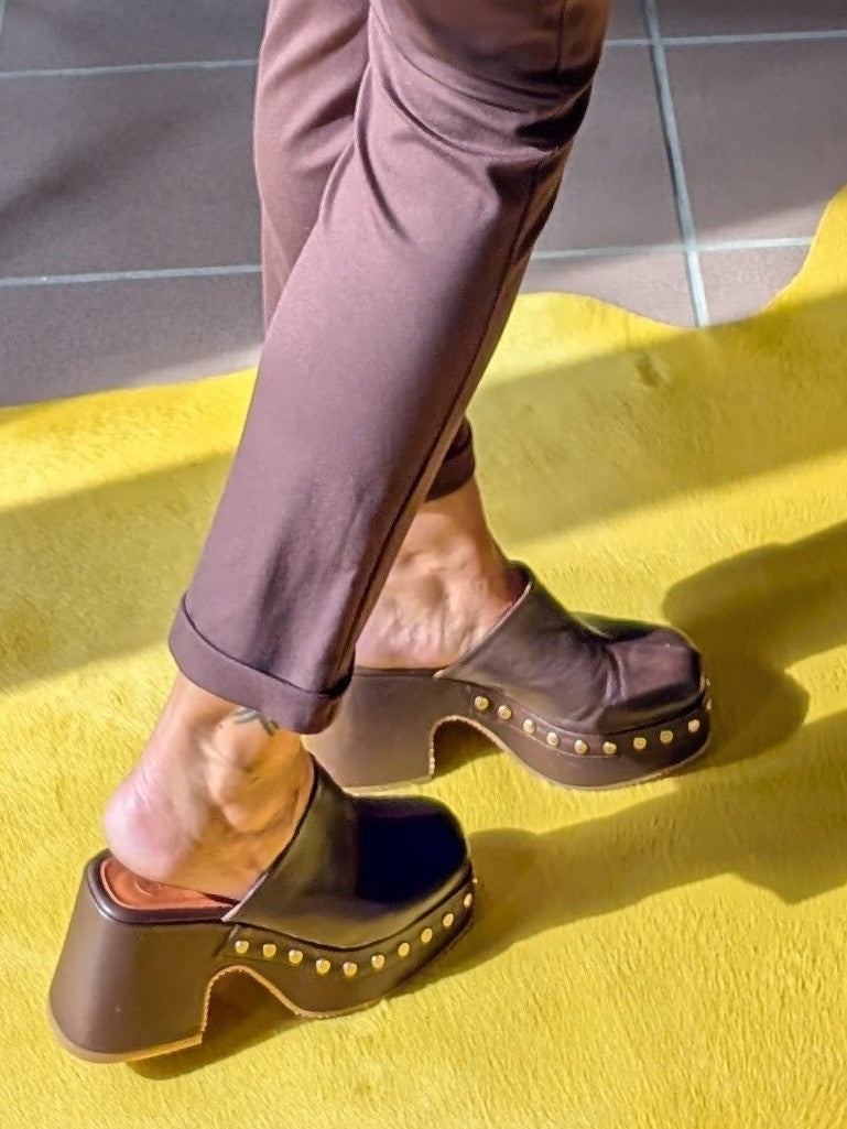 Die hochwertigen Clogs von SHADDY aus echtem Leder in Braun Maun setzen mit goldenen Nieten und einem 9 cm Plateauabsatz ein modisches Statement!