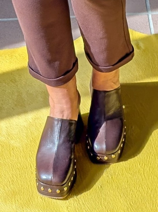 Die hochwertigen Clogs von SHADDY aus echtem Leder in Braun Maun setzen mit goldenen Nieten und einem 9 cm Plateauabsatz ein modisches Statement!