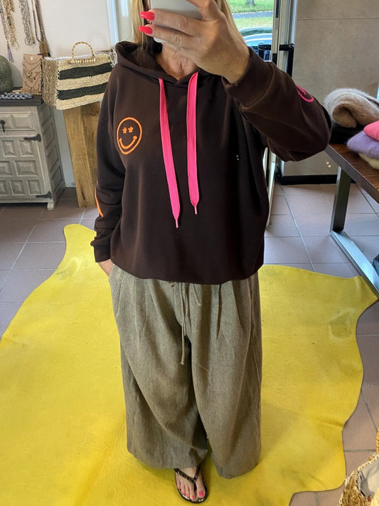 Der Hoodie von AZARA vereint warmes Coffee Braun mit Smileys und Blitzelementen in lebendigem Neon Pink, Orange und Grün in einem einzigartigen Design!