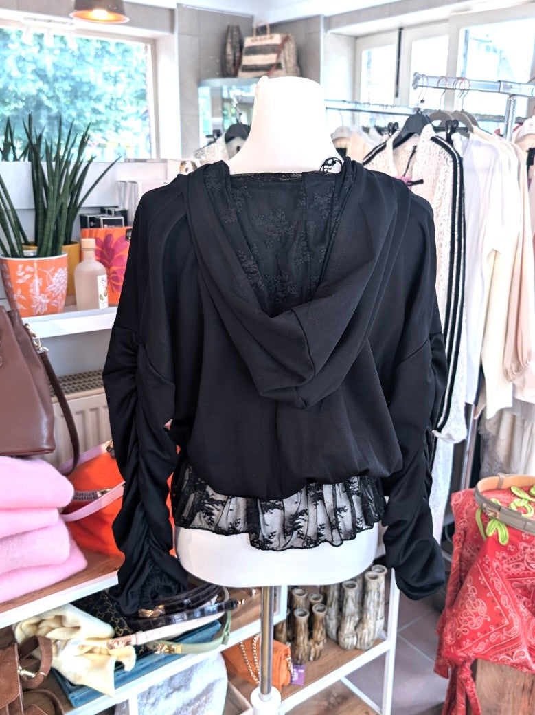 Elegante Jacke aus fließender Viskose in Schwarz mit zartem Spitzensaum, romantischen Rüschenärmeln und praktischer Kapuze - vielseitige Styling-Möglichkeiten.