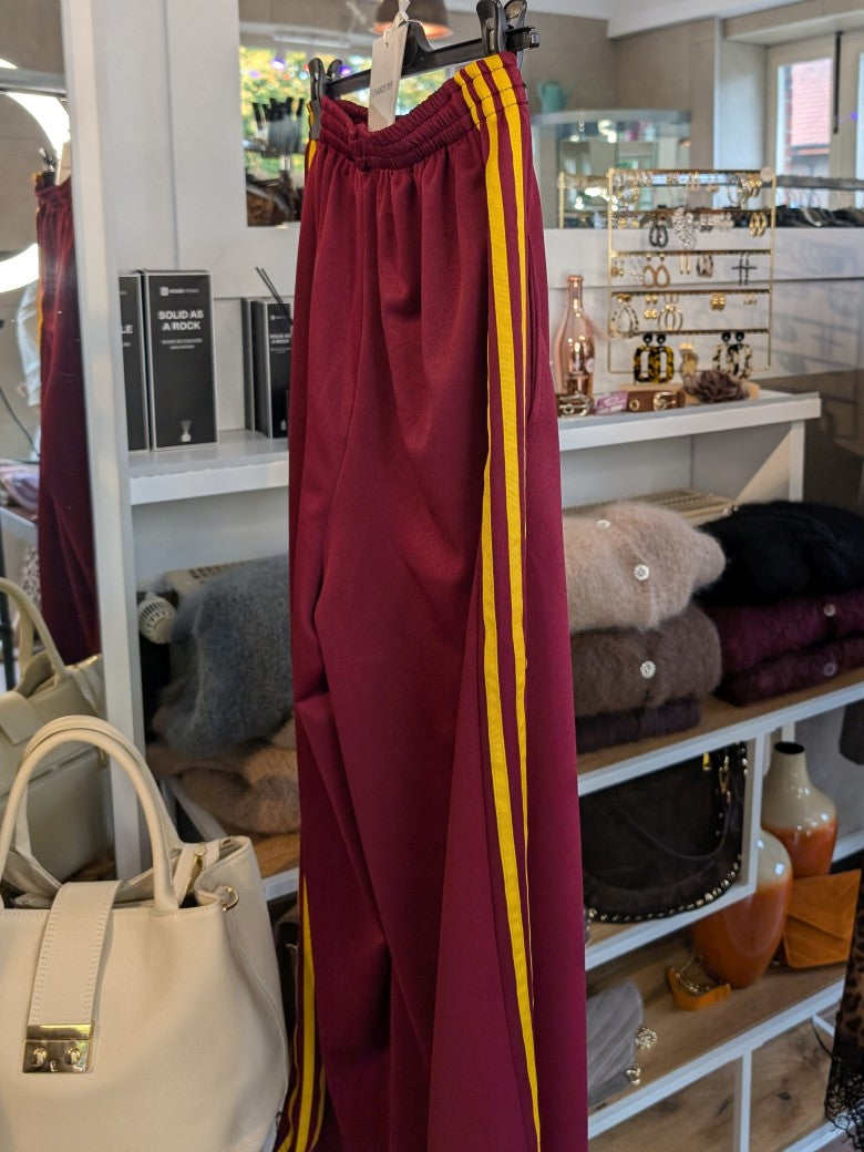 Erlebe Komfort und Style mit der trendigen Jogginghose von CHANCE OFF in Burgund Rot mit den markanten dynamischen drei Streifen in Gelb - für entspannte Tage!