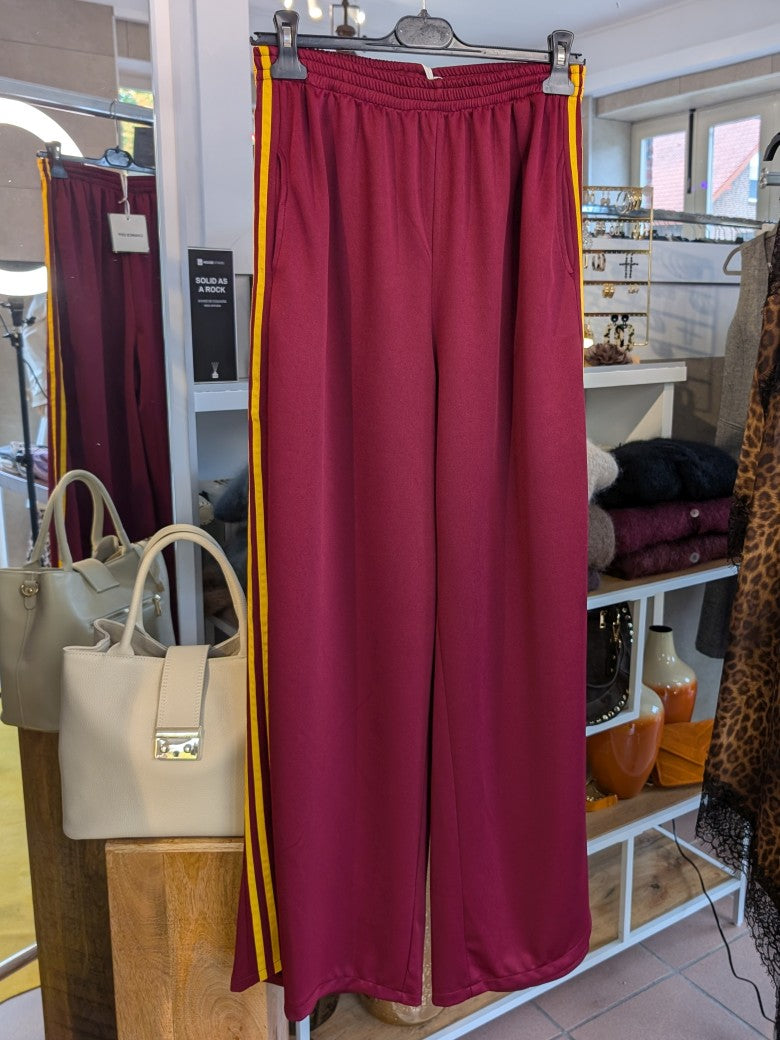 Erlebe Komfort und Style mit der trendigen Jogginghose von CHANCE OFF in Burgund Rot mit den markanten dynamischen drei Streifen in Gelb - für entspannte Tage!