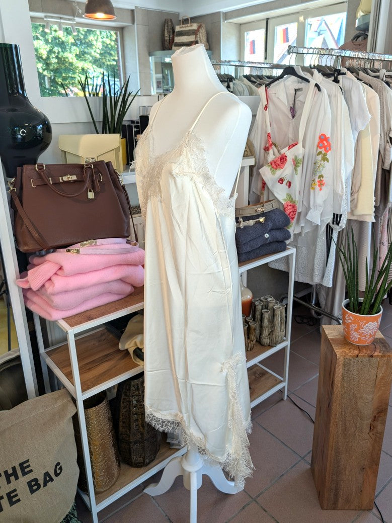 Das asymmetrische Kleid aus seidenmattem Satin in Creme kombiniert zarte Spitze und weiches Innenfutter für höchsten Tragekomfort - wirkt ideal über Jeans/Pants!