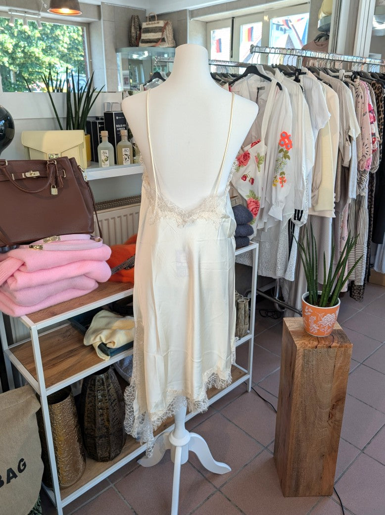 Das asymmetrische Kleid aus seidenmattem Satin in Creme kombiniert zarte Spitze und weiches Innenfutter für höchsten Tragekomfort - wirkt ideal über Jeans/Pants!