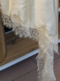 Das asymmetrische Kleid aus seidenmattem Satin in Creme kombiniert zarte Spitze und weiches Innenfutter für höchsten Tragekomfort - wirkt ideal über Jeans/Pants!