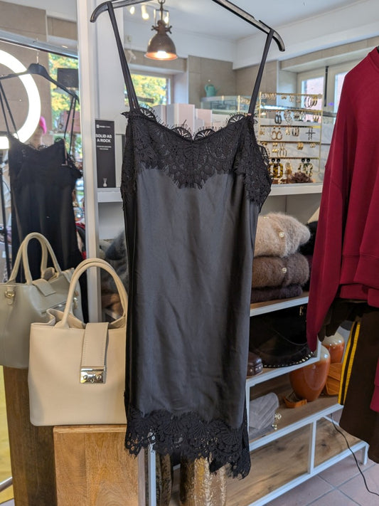Das asymmetrische Kleid aus seidenmattem Satin in Schwarz kombiniert zarte Spitze und weiches Innenfutter für höchsten Tragekomfort - wirkt ideal über Jeans!
