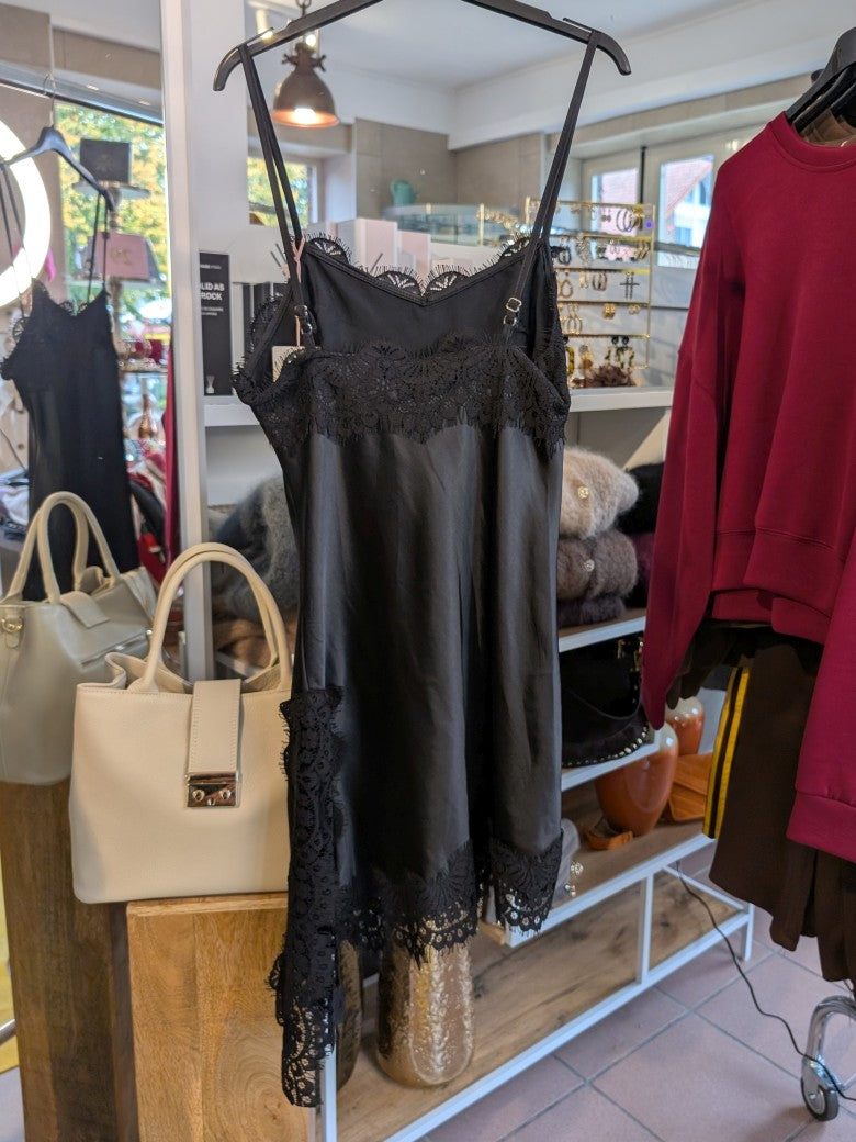 Das asymmetrische Kleid aus seidenmattem Satin in Schwarz kombiniert zarte Spitze und weiches Innenfutter für höchsten Tragekomfort - wirkt ideal über Jeans!