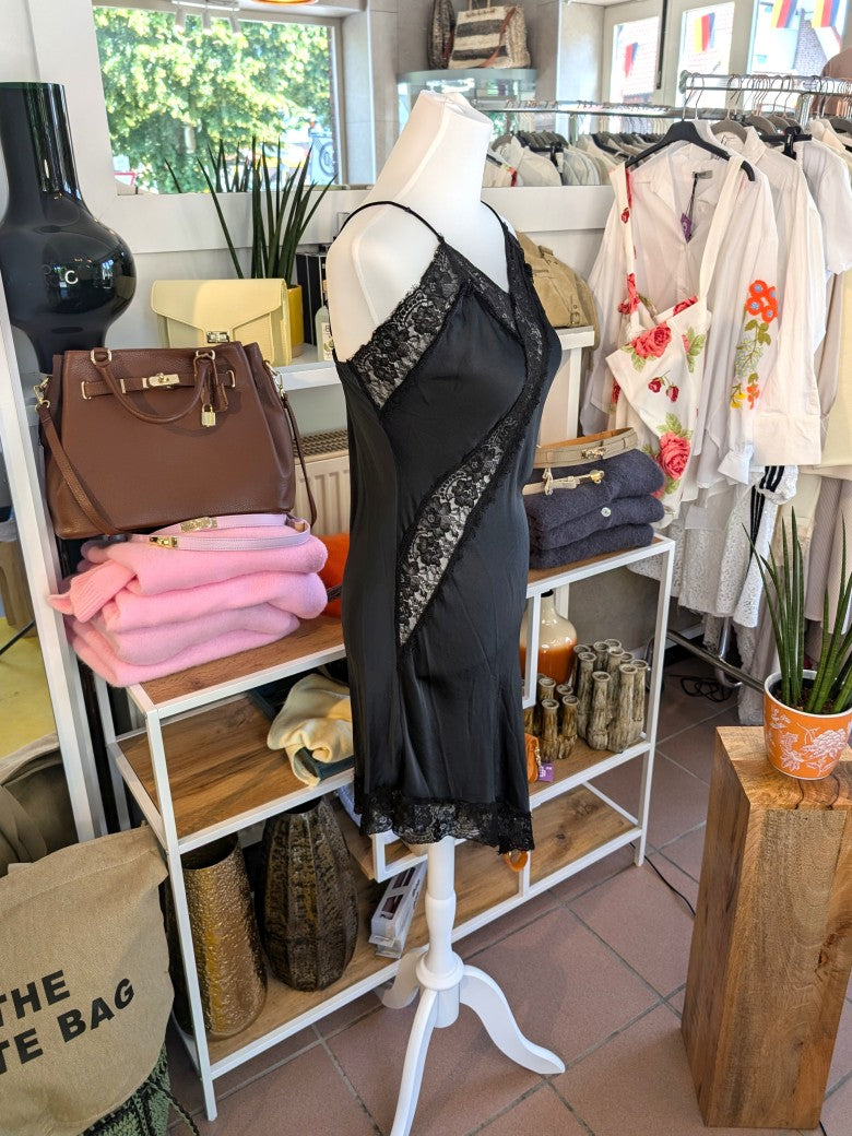 Das asymmetrische Kleid aus seidenmattem Satin kombiniert Schwarz mit schwarzer Spitze und weichem Innenfutter für höchsten Tragekomfort - wirkt ideal über Jeans!