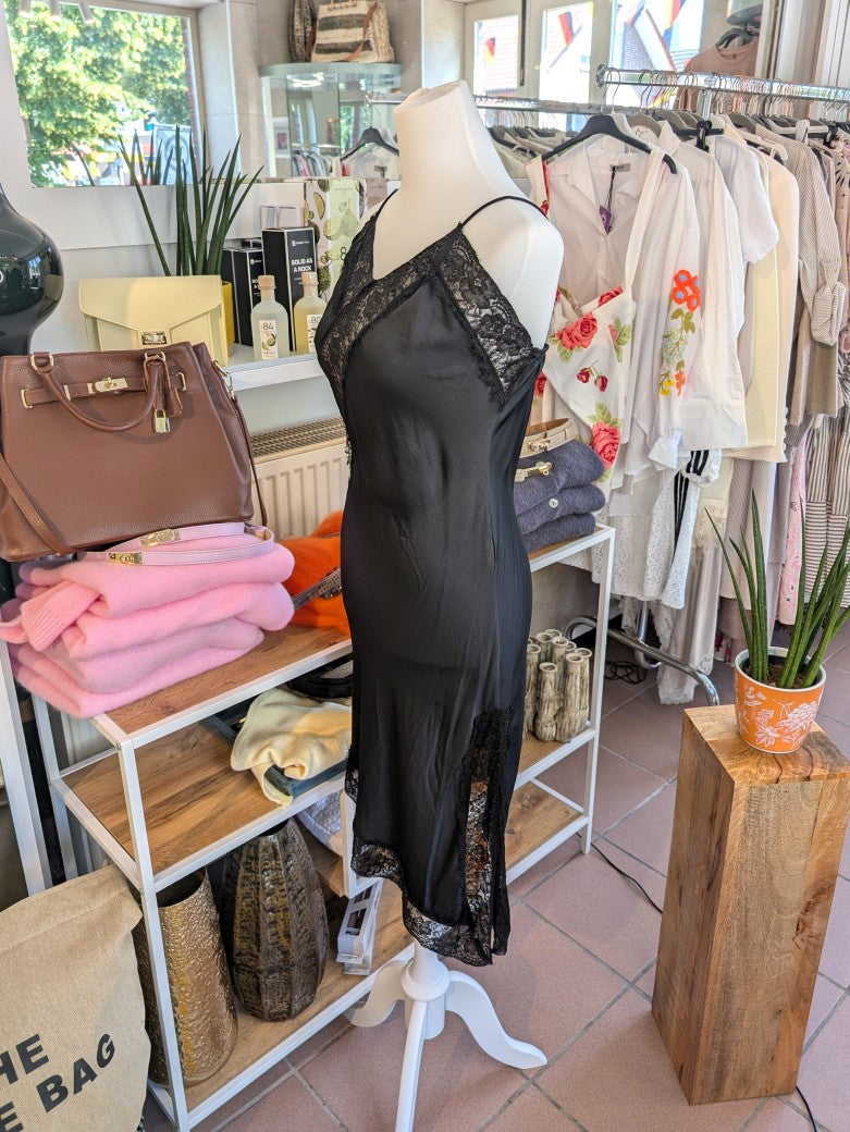 Das asymmetrische Kleid aus seidenmattem Satin kombiniert Schwarz mit schwarzer Spitze und weichem Innenfutter für höchsten Tragekomfort - wirkt ideal über Jeans!