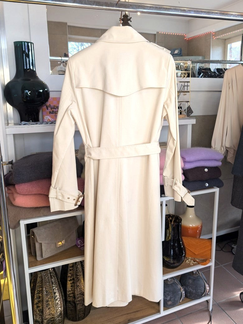 Der lange doppelreihige Trenchcoat Mantel in Creme aus Baumwolle von ATTENTIF kombiniert stilvollen Schnitt und zeitlose Eleganz für anspruchsvolle Damenmode.