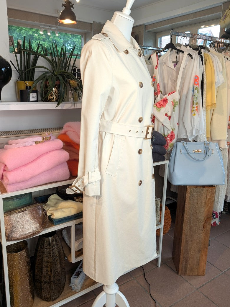 Der lange doppelreihige Trenchcoat Mantel in Creme aus Baumwolle von ATTENTIF kombiniert stilvollen Schnitt und zeitlose Eleganz für anspruchsvolle Damenmode.