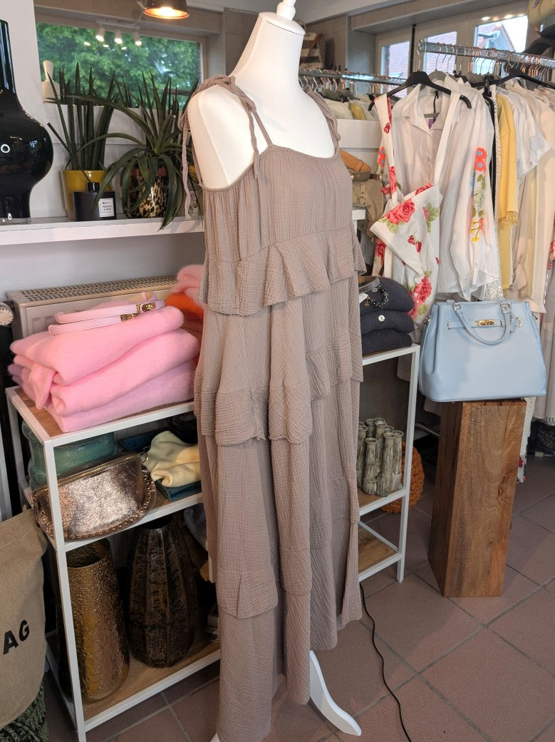 Das elegante zeitlose feminine Maxi-Kleid in Taupe aus luftigem Mousselin verzaubert mit verspielten Volants und zarten Trägern. Perfekt für sommerliche Anlässe!