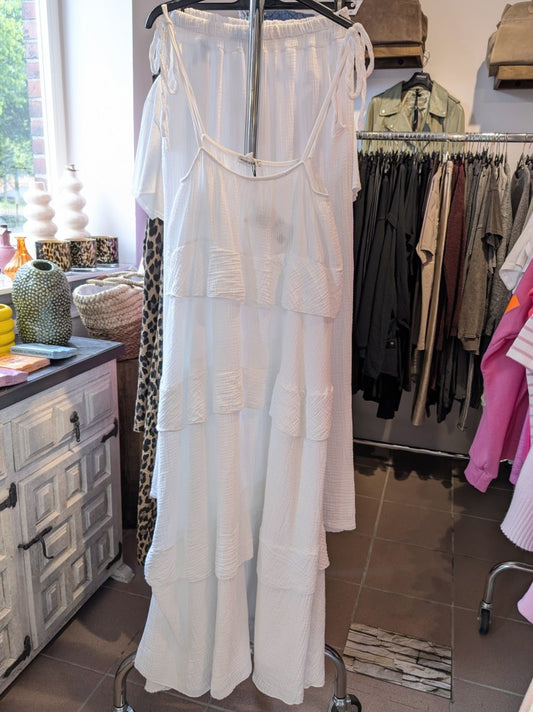 Das elegante zeitlose weiße feminine Maxi-Kleid aus luftigem Mousselin verzaubert mit verspielten Volants und zarten Trägern. Perfekt für sommerliche Anlässe!