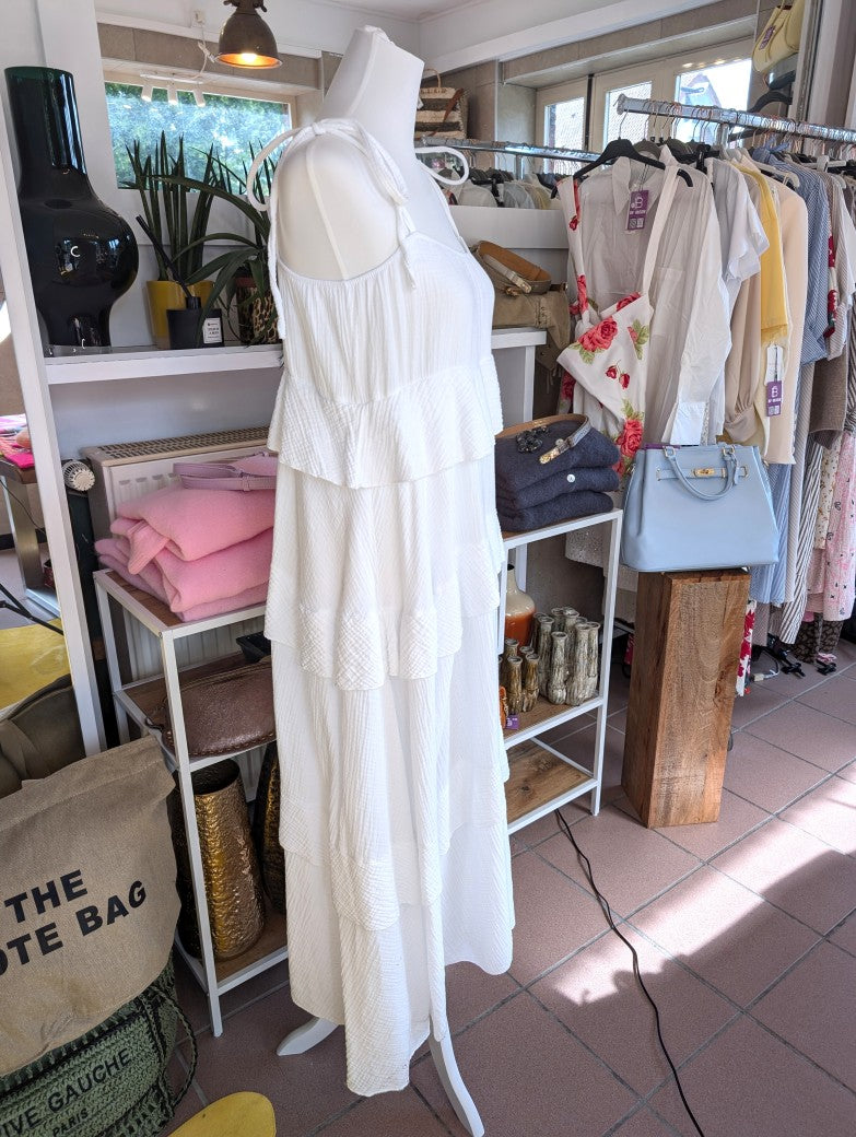 Das elegante zeitlose weiße feminine Maxi-Kleid aus luftigem Mousselin verzaubert mit verspielten Volants und zarten Trägern. Perfekt für sommerliche Anlässe!