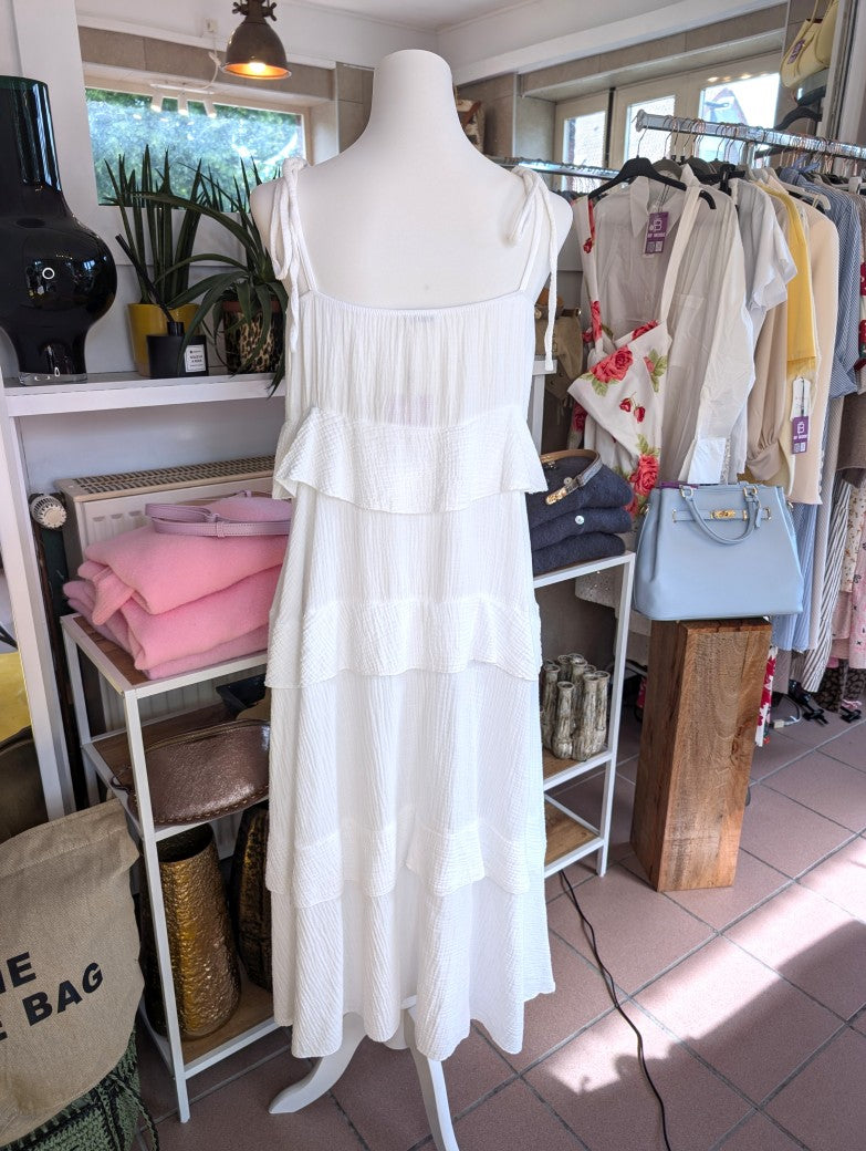 Das elegante zeitlose weiße feminine Maxi-Kleid aus luftigem Mousselin verzaubert mit verspielten Volants und zarten Trägern. Perfekt für sommerliche Anlässe!