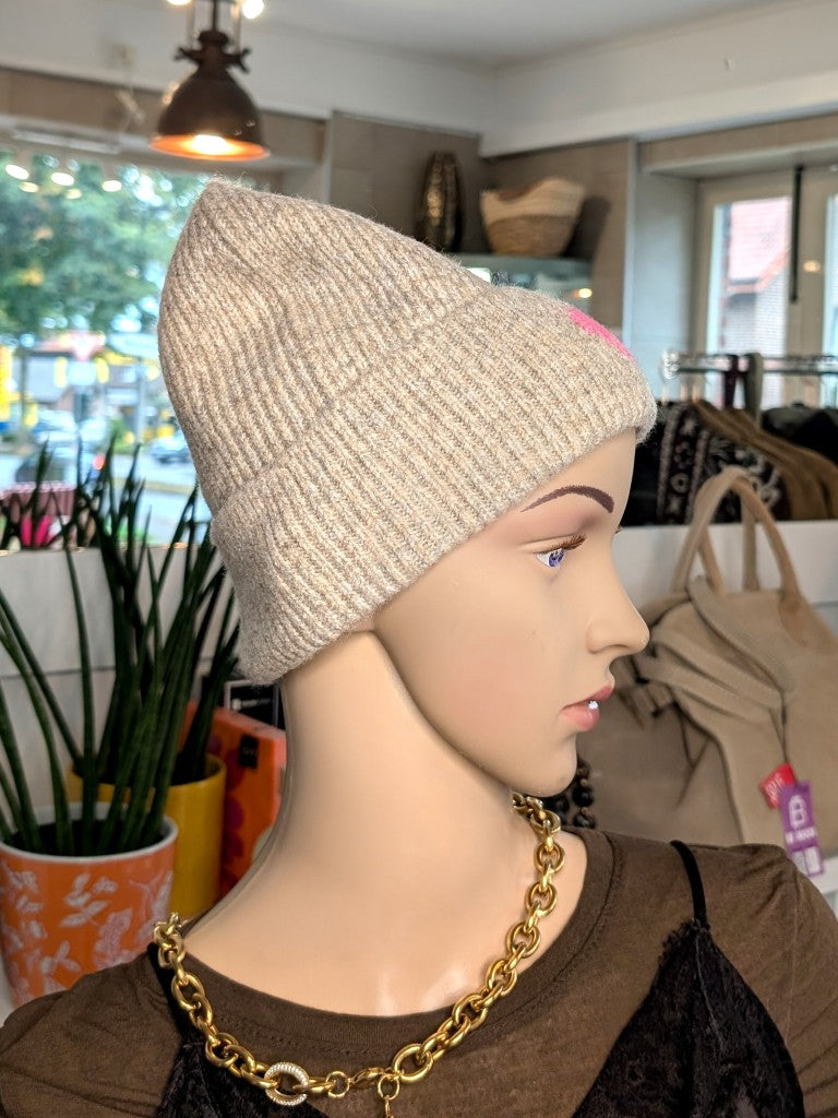 Kuschelige Wintermütze mit Umschlag aus weicher Viskose-Woll-Mischung in warmem Beige mit charmanten Herz Akzent in Pink wärmt stilvoll an kalten Tagen.