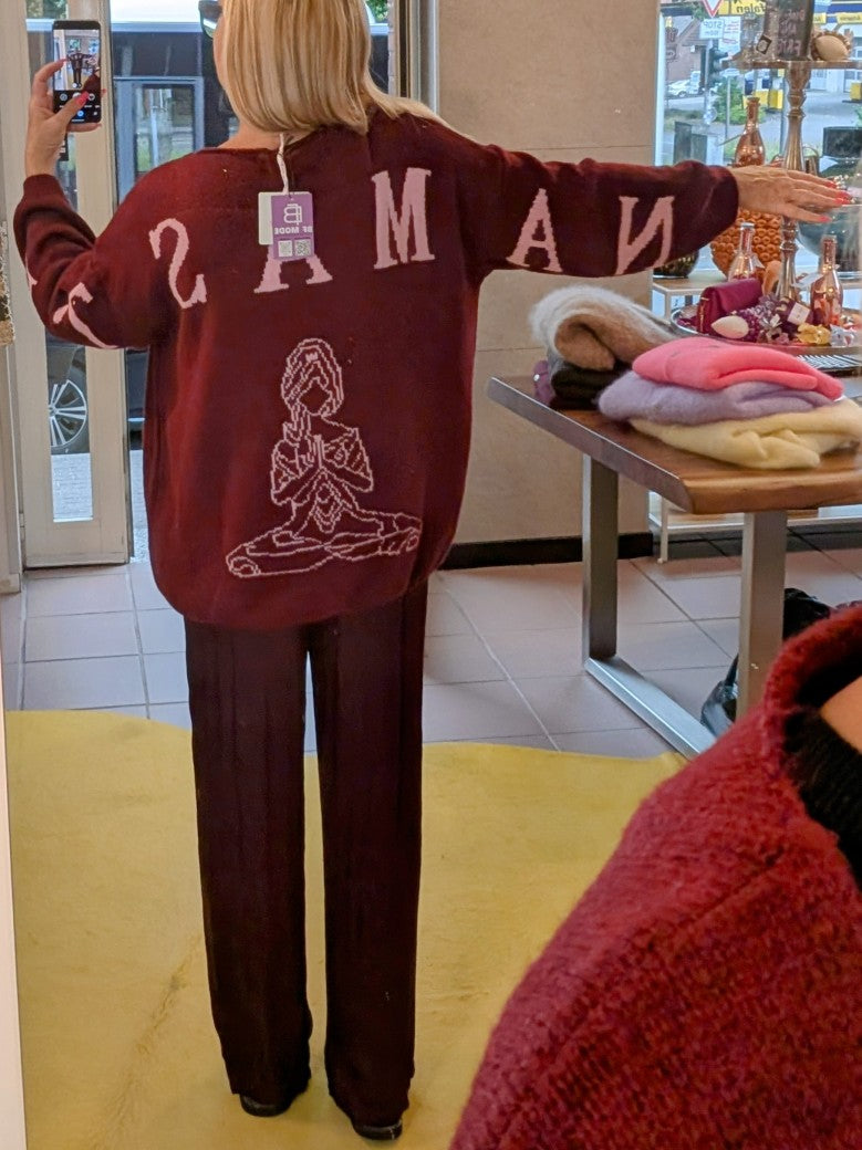 Der Pullover Namaste von BELIEVE besticht durch seinen eleganten V-Ausschnitt und den auffälligen Backprint in den Trendfarben Burgunder/Brombeere und Rosa.