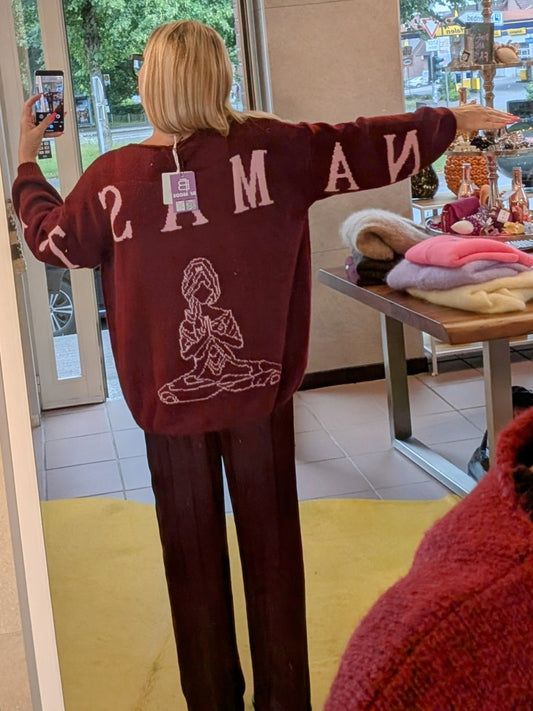 Der Pullover Namaste von BELIEVE besticht durch seinen eleganten V-Ausschnitt und den auffälligen Backprint in den Trendfarben Burgunder/Brombeere und Rosa.
