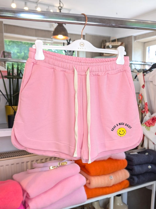 Entdecke den perfekten Sommerlook mit unser "Have A Nice Day" Smiley Shorts in Rosa aus bequemem Sweatshirtstoff. Ideal und auffallend für heiße Tage!