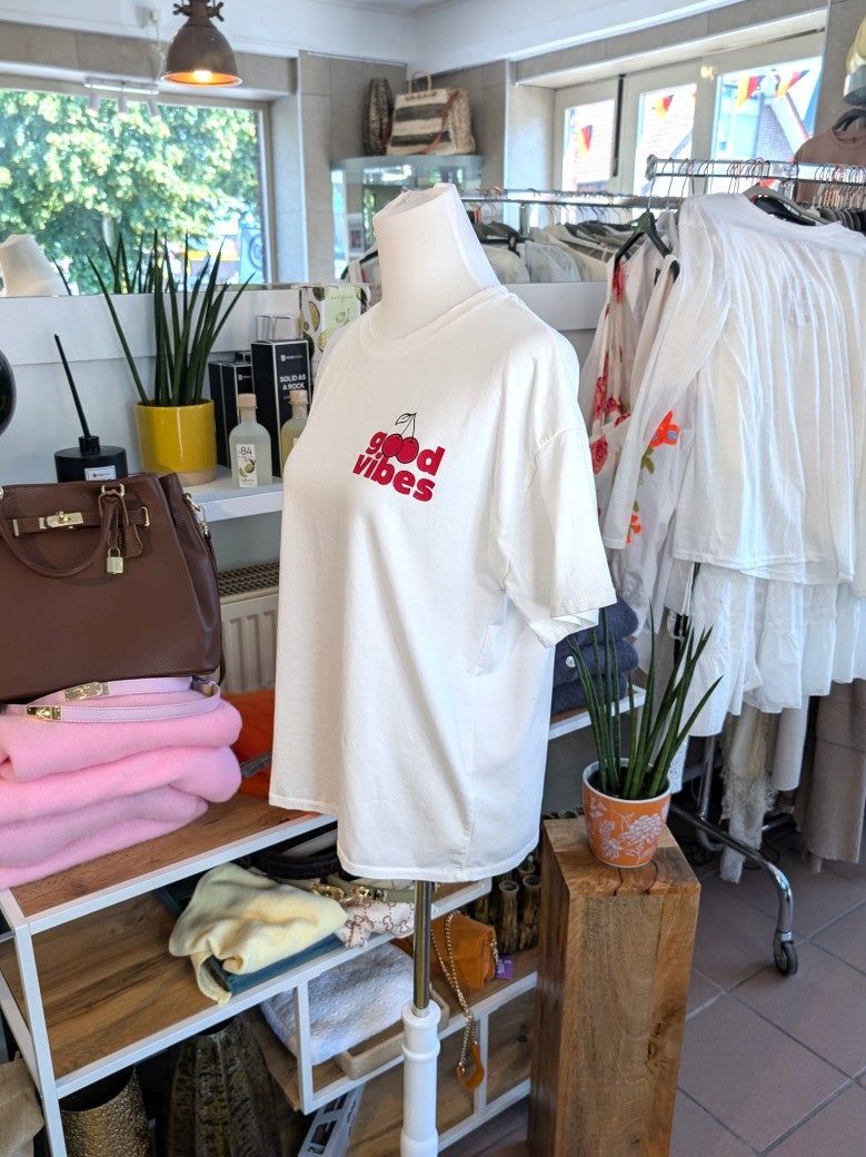 Lässiges T-Shirt in hellem Créme mit farbenfrohem Kirsch-Backprint in Rot, Gelb, Grün und Orange. Statement-Piece von Mioni für gute Laune und positive Energie.