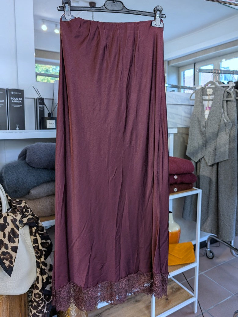 Verleihe deinem Outfit einen Hauch von Eleganz mit diesem langen Satin Rock aus Viskose in Burgund Rot mit brauner Spitze. Perfekt für das gewisse Etwas!