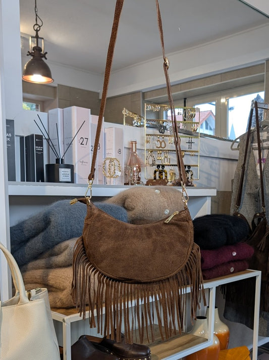 Die Wildledertasche in warmem Braun überzeugt mit Halbmond-Form, Schulterriemen, RV und stilvollen Fransen - verleiht jedem Outfit eine trendige Note!